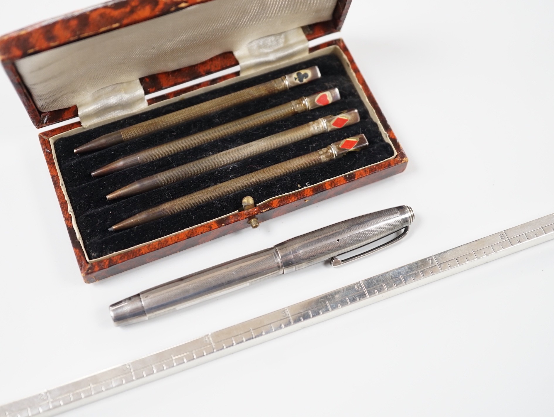 An engine-turned silver fountain pen, a cased set of four silver Bridge pencils and a silver combination pencil/rule